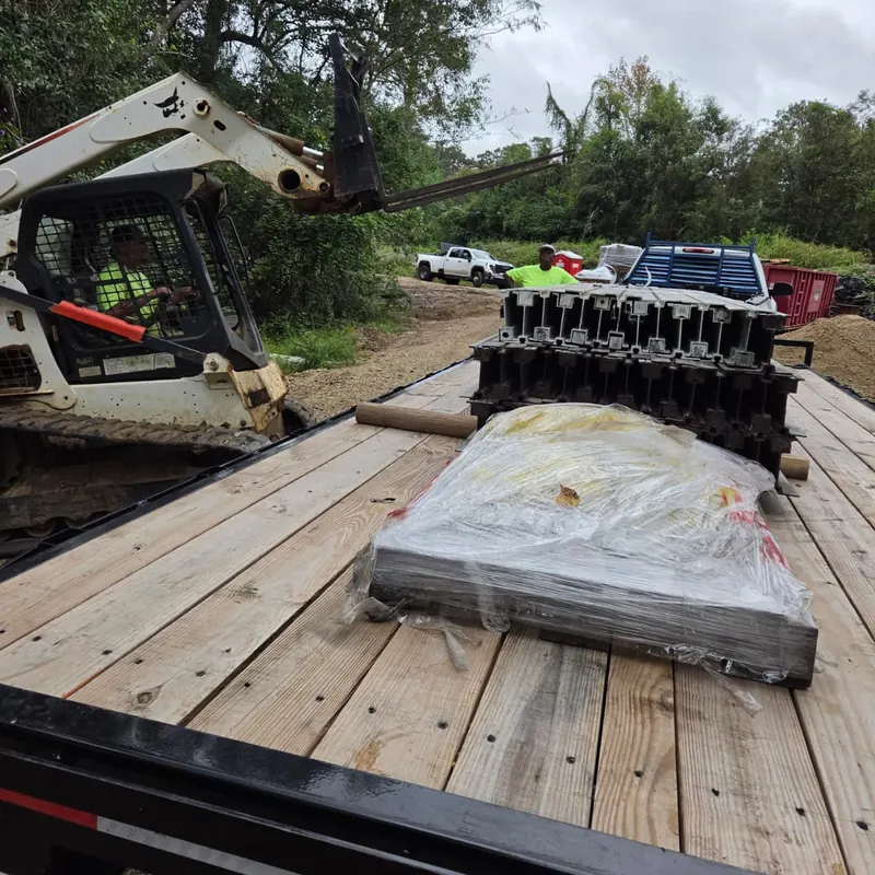 Skid steer loading construction materials onto a flatbed trailer at a job site