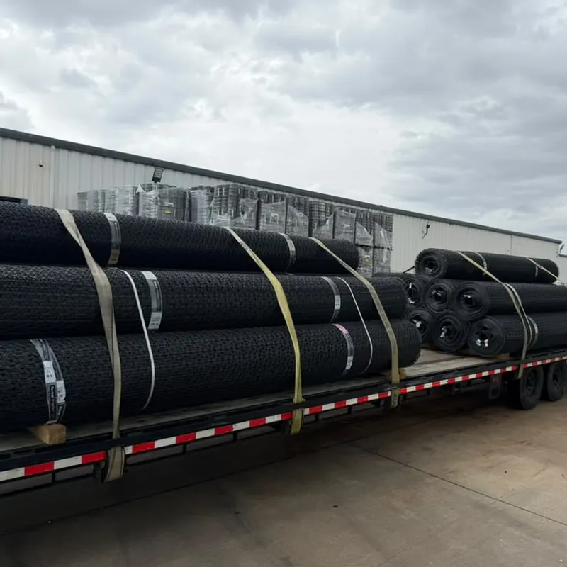 Rolls of mesh strapped down on a gooseneck flatbed trailer outside a warehouse