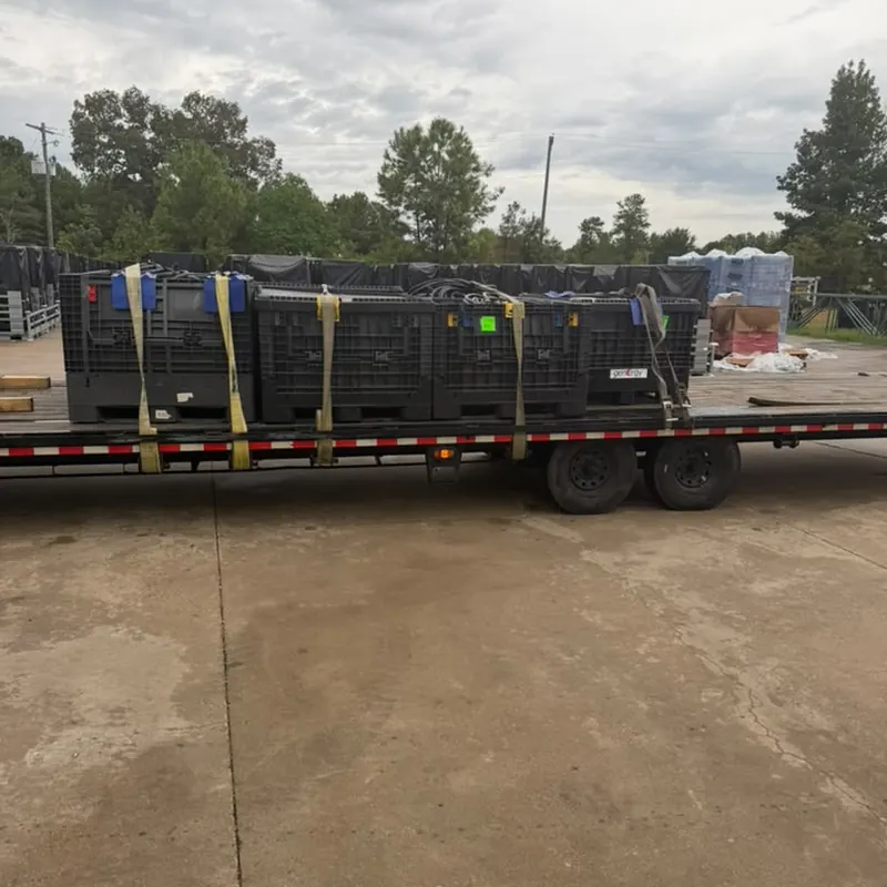 Bulk plastic totes secured with straps on a flatbed trailer